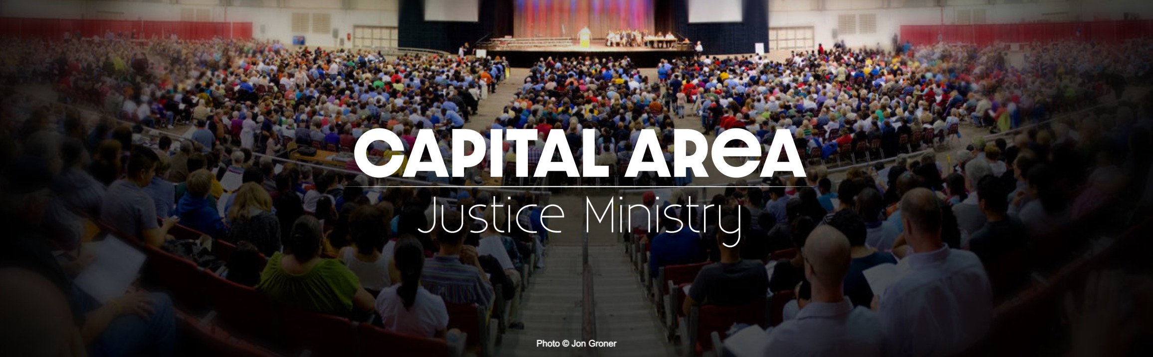 Capital Area Justice Ministry's logo on top of a photo of a large room full of people looking at a central podium