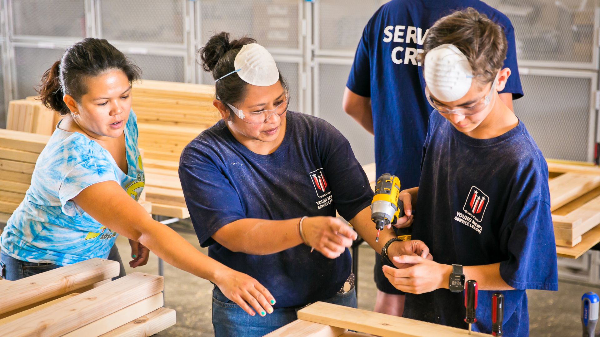 Two women help a teenage boy build a bed