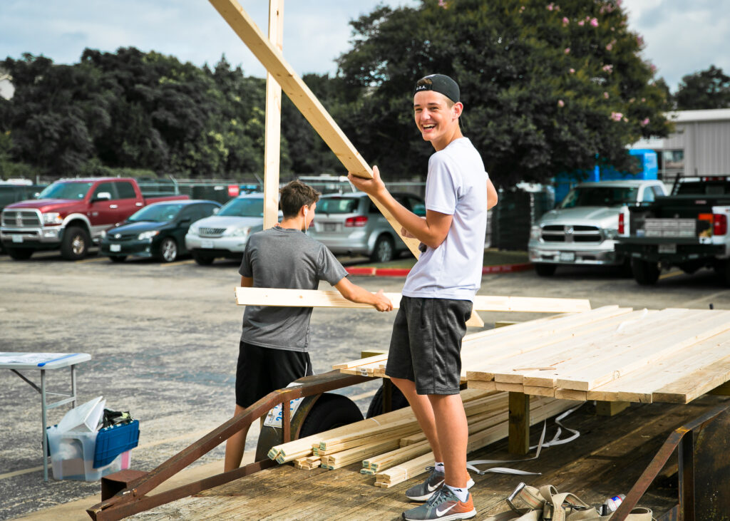 Teenage boy carrying lumber for the bed build